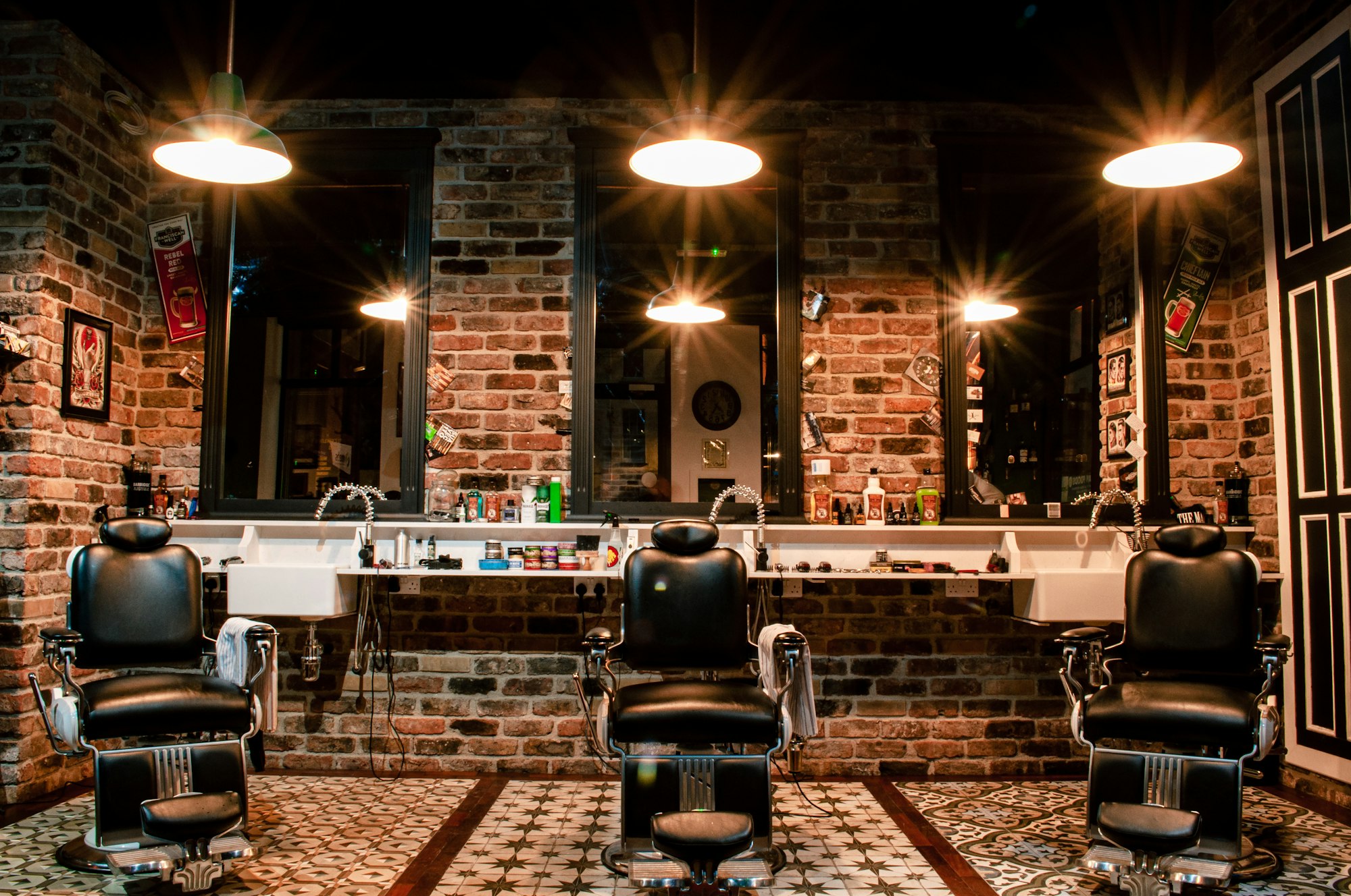 Interior de barbería con sillones de cuero negro y pared de ladrillo visto